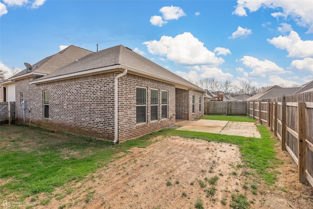 back of property with a yard and a patio