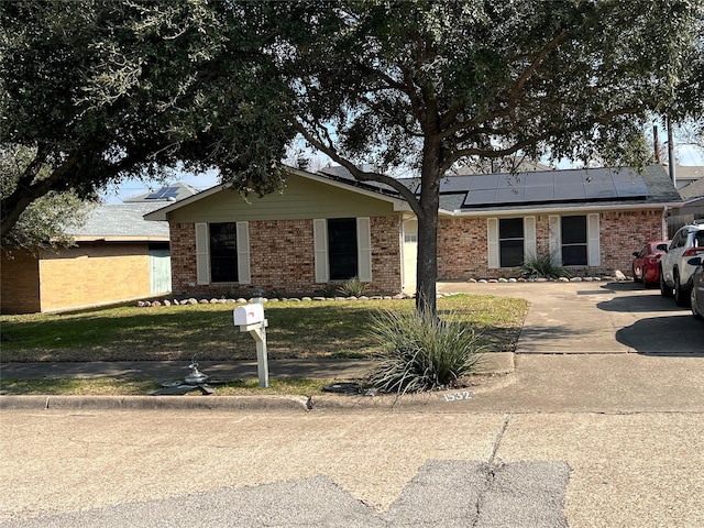 ranch-style home featuring a front lawn and solar panels