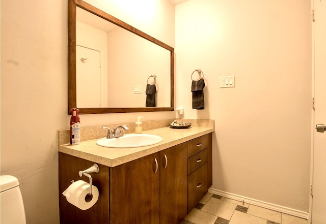 half bathroom featuring toilet, baseboards, and vanity