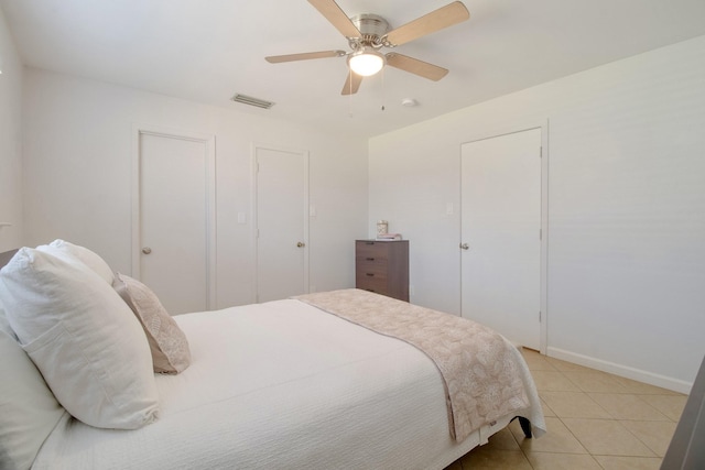 bedroom featuring light tile patterned floors, baseboards, visible vents, and a ceiling fan