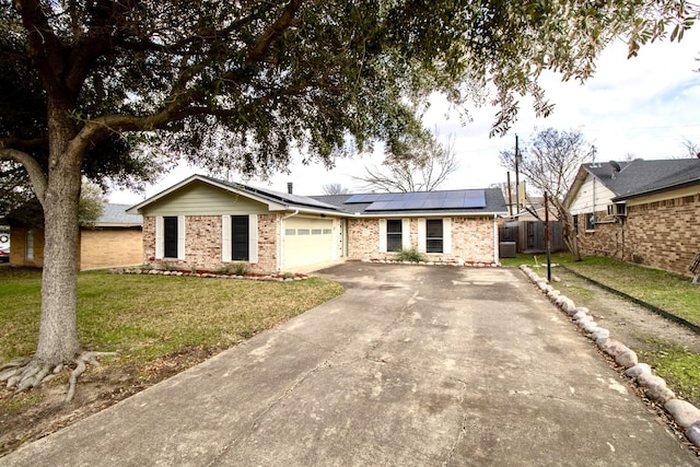 ranch-style house with solar panels, concrete driveway, an attached garage, fence, and a front lawn