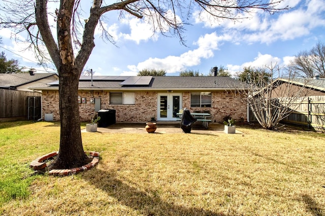 rear view of house with a yard, a fenced backyard, a patio, and french doors