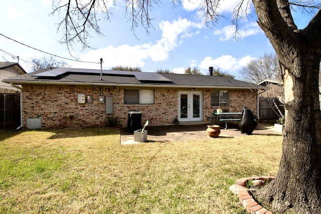 rear view of house with a patio area, french doors, brick siding, and a lawn