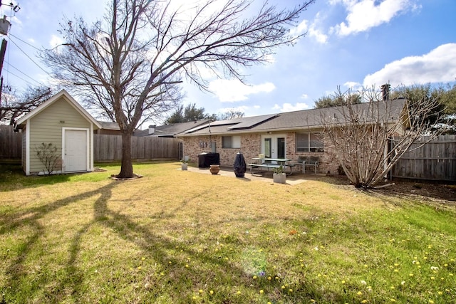 view of yard with a fenced backyard, an outdoor structure, a shed, and a patio