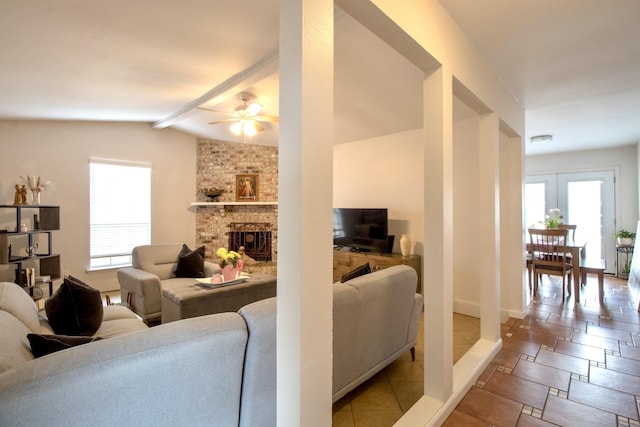 living room with vaulted ceiling with beams, a brick fireplace, plenty of natural light, and baseboards