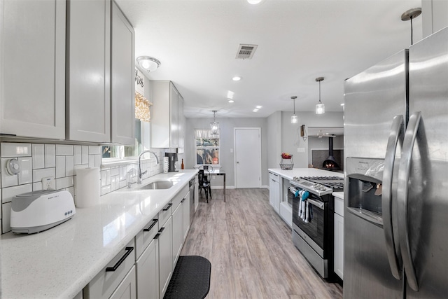 kitchen with pendant lighting, sink, white cabinets, light stone counters, and stainless steel appliances