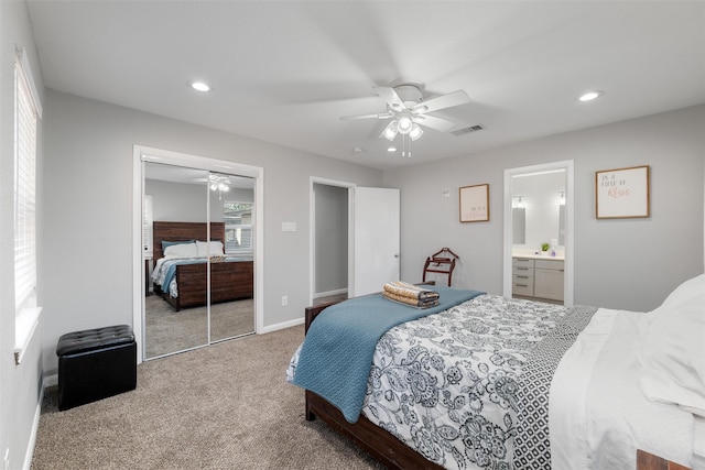 carpeted bedroom with ensuite bath, ceiling fan, and a closet