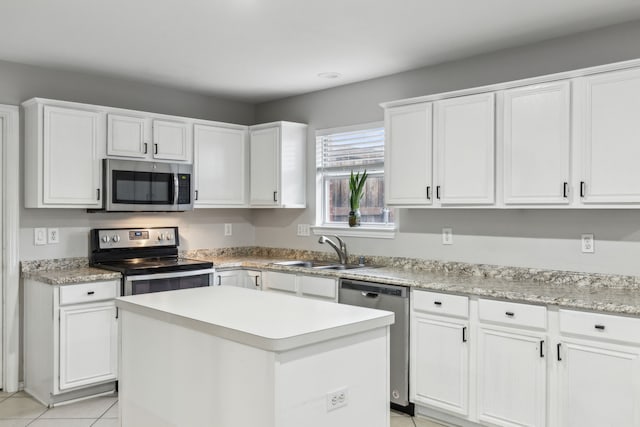 kitchen with sink, stainless steel appliances, a center island, white cabinets, and light tile patterned flooring