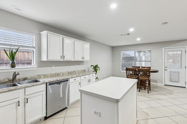 kitchen with sink, dishwasher, a kitchen island, white cabinets, and light tile patterned flooring