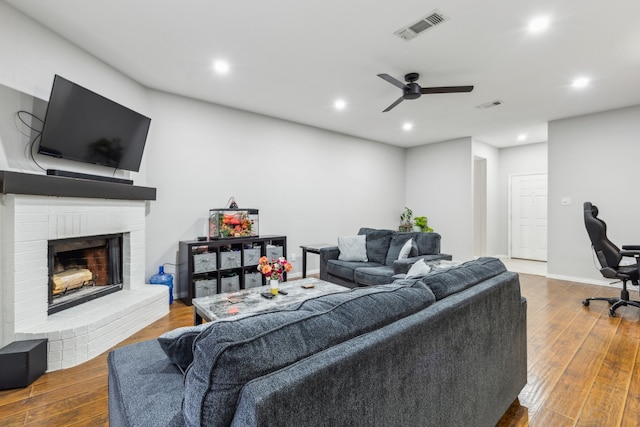 living room with a brick fireplace, hardwood / wood-style floors, and ceiling fan