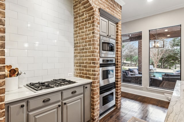 kitchen with light stone counters, gray cabinetry, dark hardwood / wood-style floors, crown molding, and stainless steel appliances