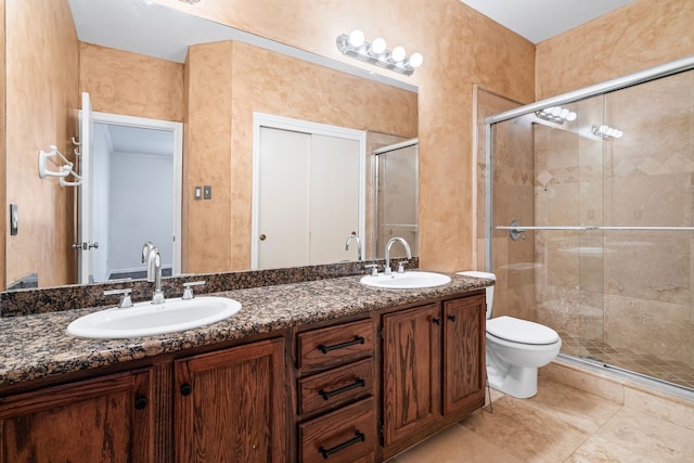 bathroom featuring tile patterned flooring, vanity, a shower with shower door, and toilet