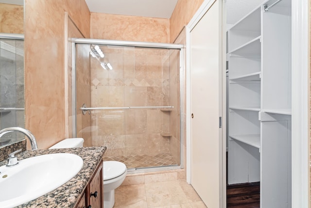 bathroom featuring tile patterned floors, vanity, toilet, and a shower with shower door