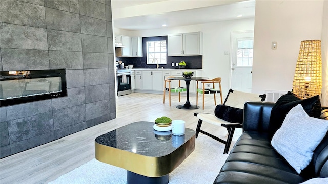 living room featuring a large fireplace, sink, and light hardwood / wood-style floors