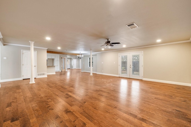 unfurnished living room with ceiling fan with notable chandelier, decorative columns, light hardwood / wood-style floors, crown molding, and french doors