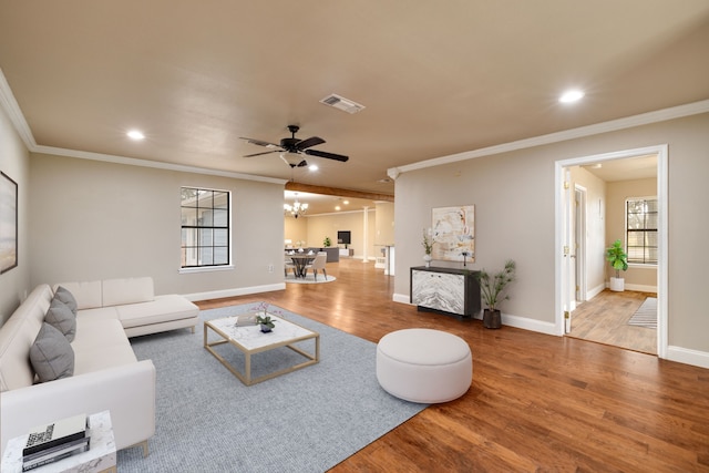 living room featuring ceiling fan with notable chandelier, ornamental molding, and hardwood / wood-style floors