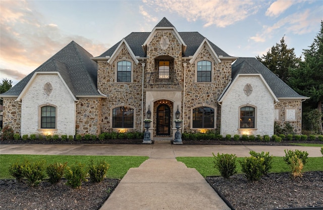 french country style house featuring a balcony and a shingled roof