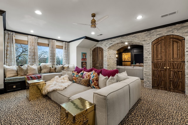 cinema room featuring ceiling fan, crown molding, brick wall, and carpet