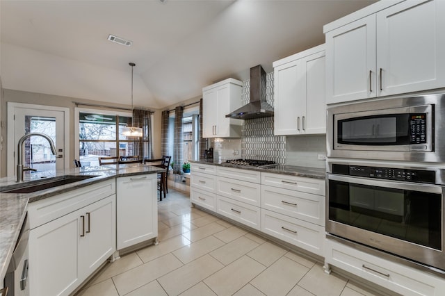 kitchen with sink, wall chimney exhaust hood, stainless steel appliances, white cabinets, and light stone counters