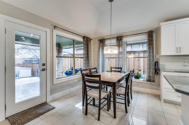 dining area featuring an inviting chandelier, plenty of natural light, vaulted ceiling, and light tile patterned flooring