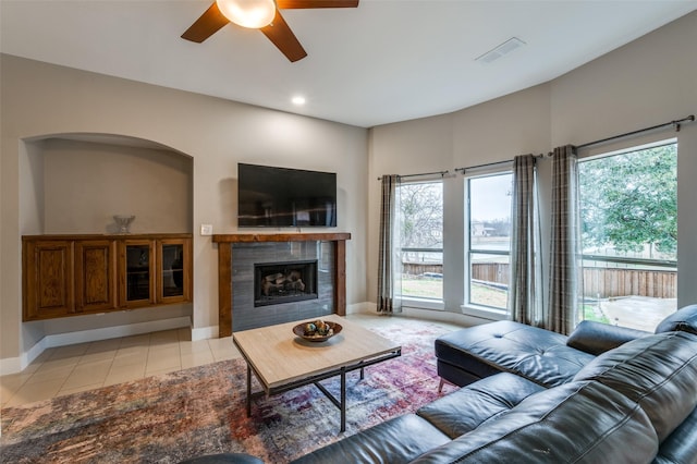 living room featuring a healthy amount of sunlight, light tile patterned floors, ceiling fan, and a fireplace