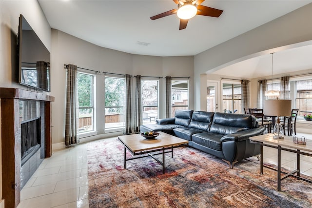 living room with a tile fireplace, light tile patterned floors, and ceiling fan