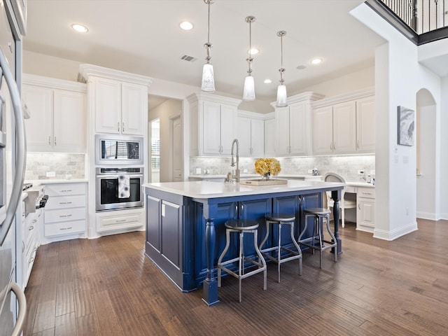 kitchen featuring appliances with stainless steel finishes, a kitchen island with sink, a breakfast bar area, and white cabinets