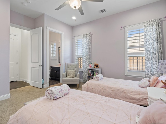 bedroom featuring ceiling fan, ensuite bathroom, and dark carpet