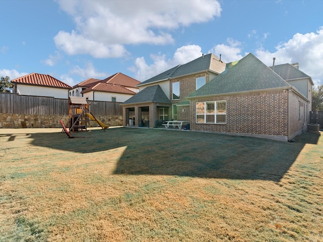 back of property featuring a lawn and a playground