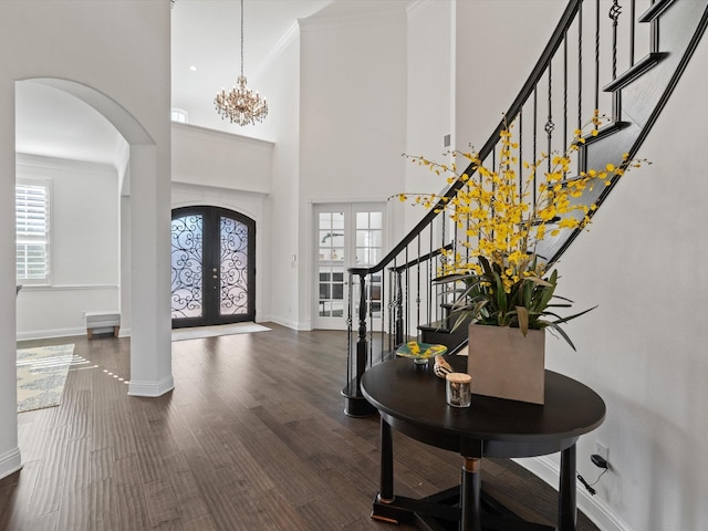 entrance foyer featuring french doors, a towering ceiling, ornamental molding, and dark hardwood / wood-style flooring