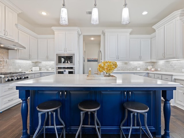 kitchen with white cabinetry, stainless steel appliances, a center island, and pendant lighting