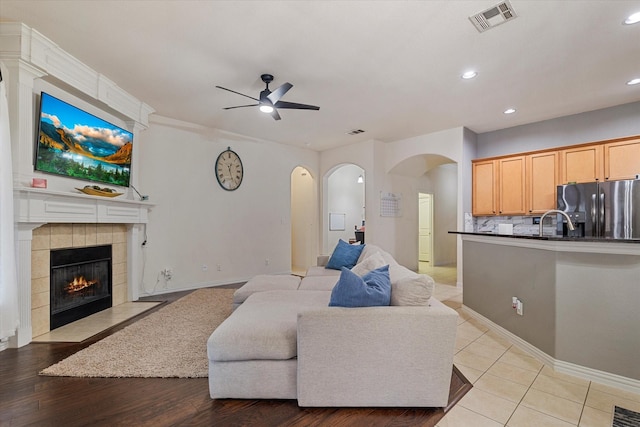 living room featuring a tile fireplace and ceiling fan