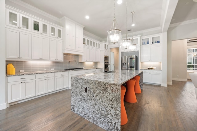 kitchen featuring stainless steel appliances, white cabinetry, glass insert cabinets, and an island with sink