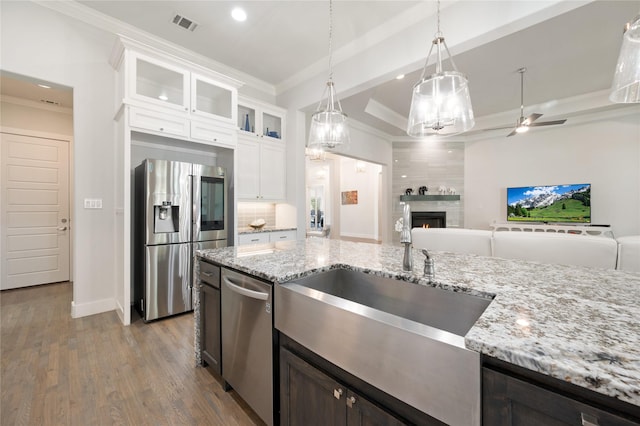 kitchen featuring glass insert cabinets, open floor plan, stainless steel appliances, crown molding, and white cabinetry