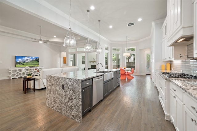 kitchen featuring stainless steel appliances, white cabinetry, open floor plan, an island with sink, and decorative light fixtures