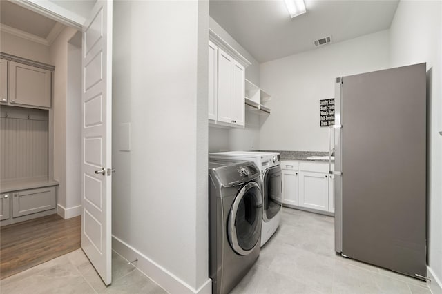 laundry area featuring cabinet space, baseboards, visible vents, washer and clothes dryer, and crown molding