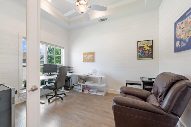 office space featuring ceiling fan, light wood-style flooring, a raised ceiling, and visible vents