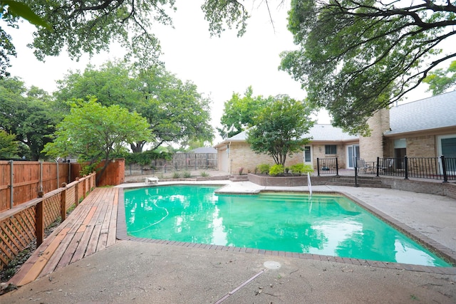 view of swimming pool featuring a patio and a diving board