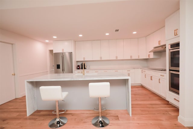 kitchen with white cabinetry, appliances with stainless steel finishes, a kitchen island with sink, and sink