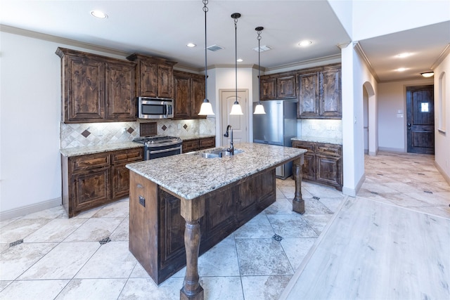 kitchen with an island with sink, sink, a breakfast bar area, hanging light fixtures, and stainless steel appliances