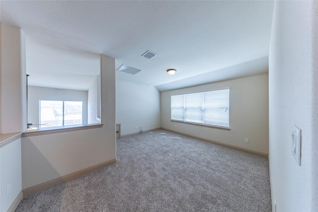 carpeted spare room featuring lofted ceiling and a textured ceiling