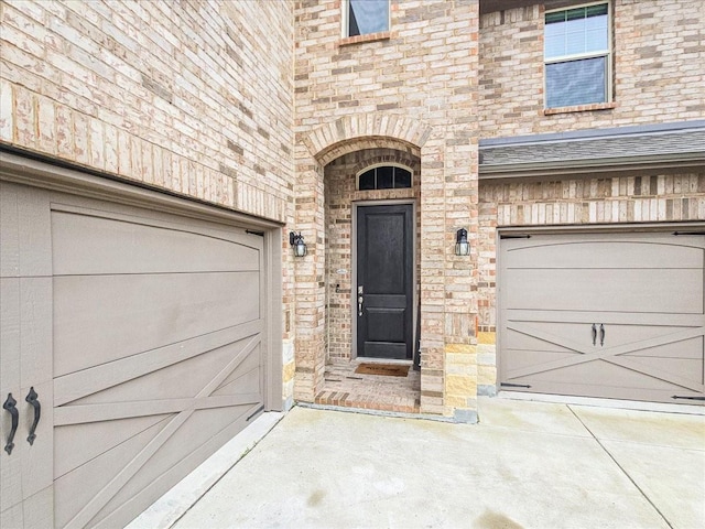 entrance to property featuring a garage and brick siding