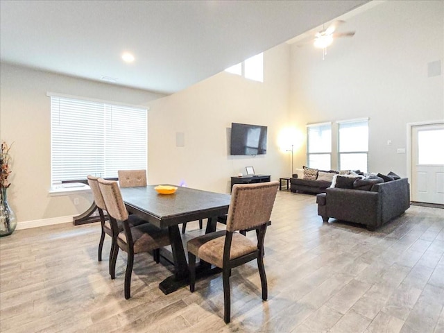 dining room with light wood-style flooring, a high ceiling, and baseboards