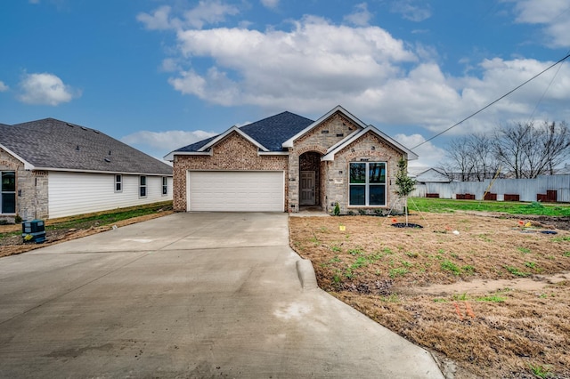 view of front facade with concrete driveway, brick siding, and fence