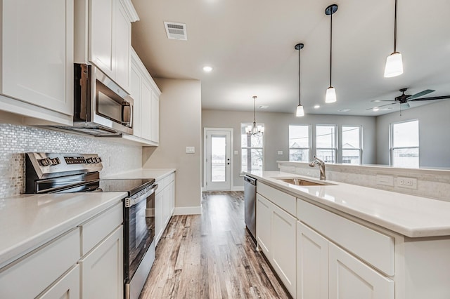 kitchen with stainless steel appliances, light countertops, and white cabinets