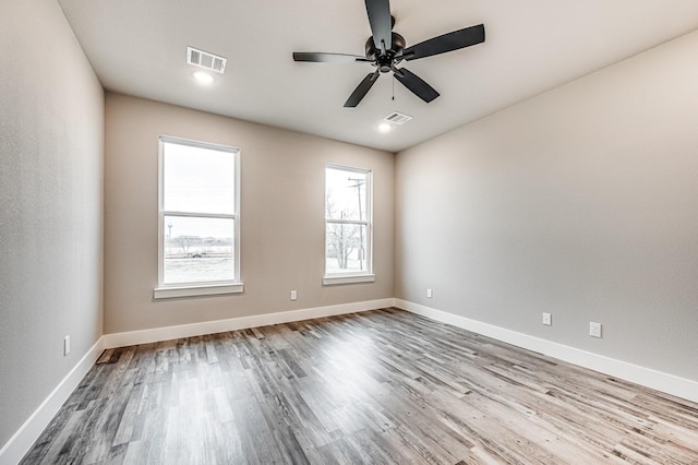 spare room with baseboards, visible vents, and wood finished floors