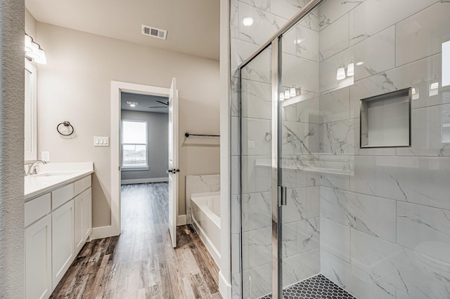 full bathroom with wood finished floors, vanity, baseboards, a shower stall, and a bath