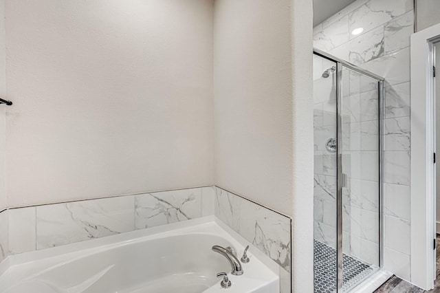 bathroom featuring a stall shower and a bath