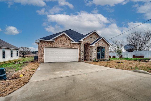 view of front of home featuring driveway, a garage, a shingled roof, fence, and brick siding