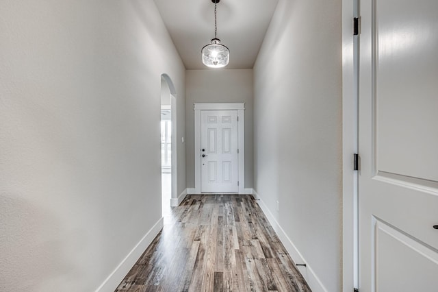 entryway featuring arched walkways, wood finished floors, and baseboards